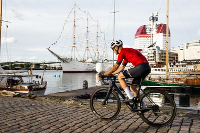 A man wearing a red shirt near the water during the day to ride a bicycle
